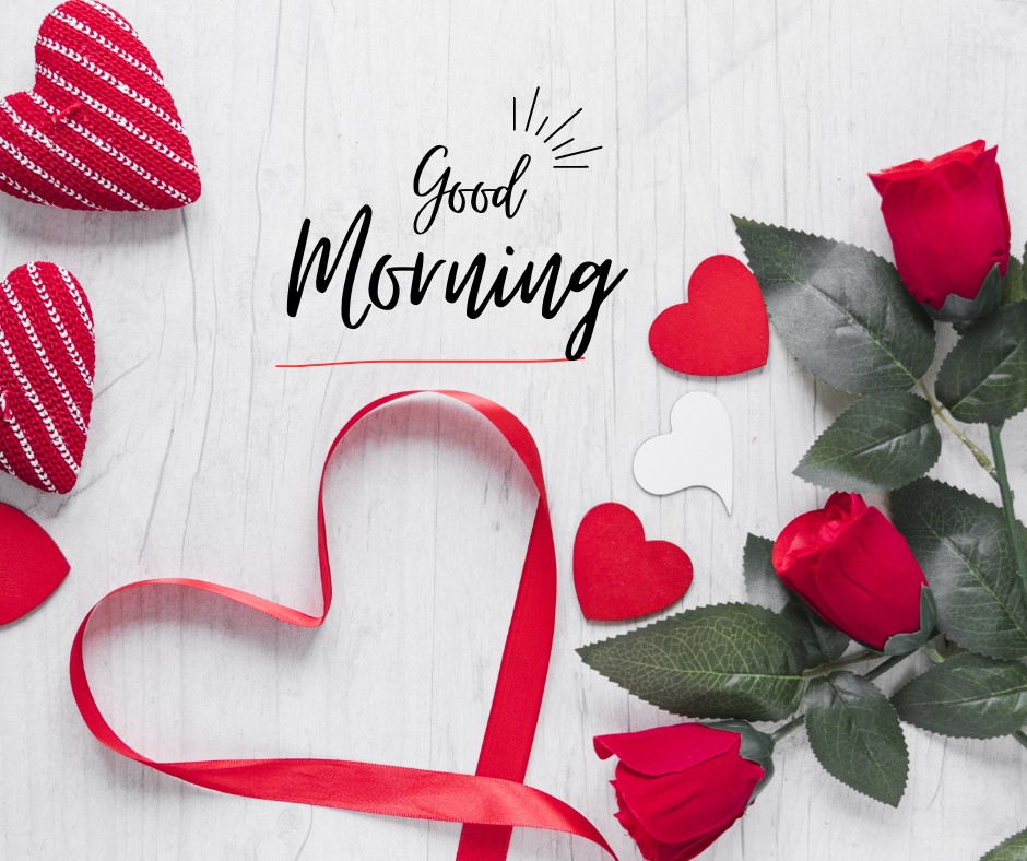 An elegant composition of red roses, heart-shaped decorations, and a romantic ribbon forming a heart on a white wooden background. The script "Good Morning" adds a stylish touch to the image. This charming and loving setup is perfect for posts titled "Good Morning Red Rose Images," ideal for conveying warm, heartfelt greetings.