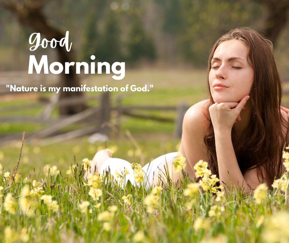 A serene image of a woman lying in a meadow filled with yellow flowers, eyes closed and face uplifted towards the sky, with the text "Good Morning" and the quote "Nature is my manifestation of God." in the background. This beautiful morning scene captures the tranquility and divine connection with nature, ideal for a peaceful start to the day.