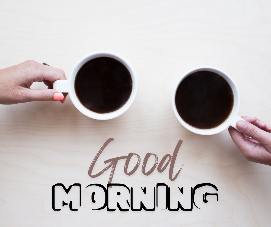 Shared good morning coffee moment with two hands holding white cups of black coffee over a light wooden table, featuring a stylish 'Good Morning' inscription in the center.