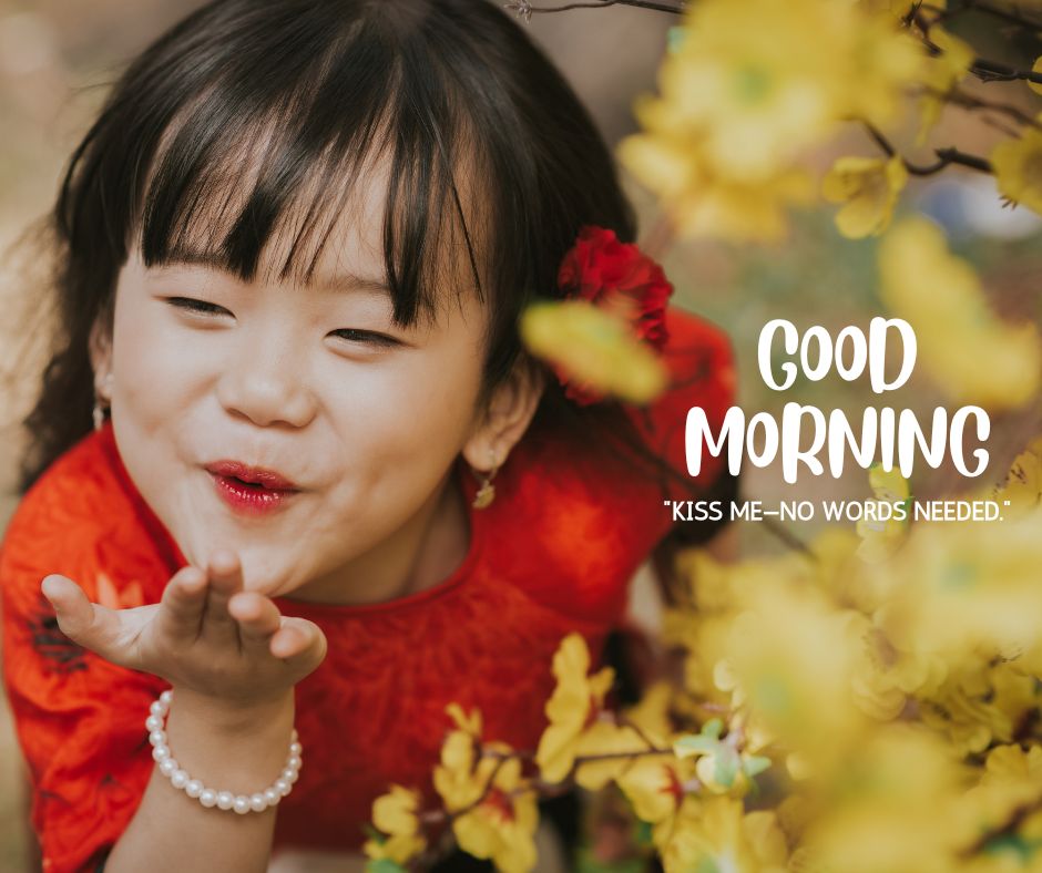 Adorable young girl in a red dress blowing a kiss surrounded by yellow blossoms, with 'GOOD MORNING' text and a sweet quote about a kiss needing no words.